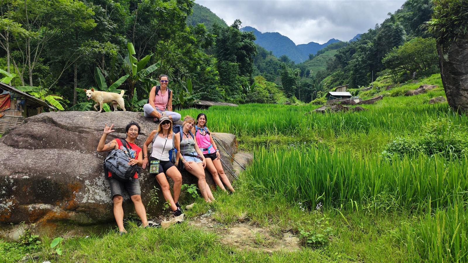 Travelers resting on a boulder overlooking Sapa's rice terraces
